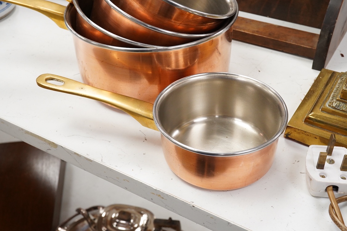 A graduated set of 5 copper brass handled sauce pans and a copper embossed and mahogany hanging rack